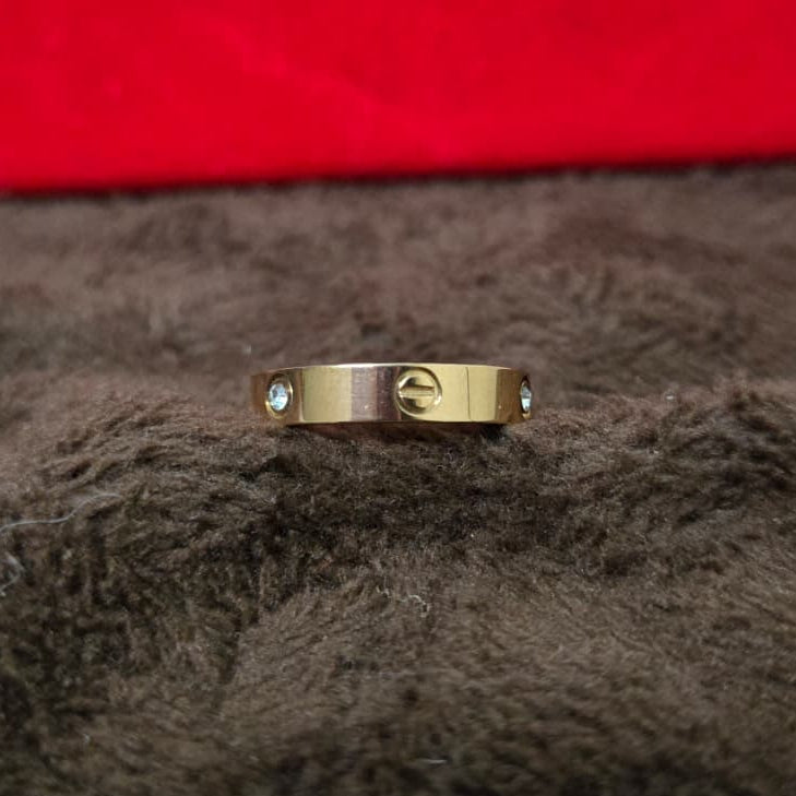 Gold ring with small stones on a brown surface, red box in the background
