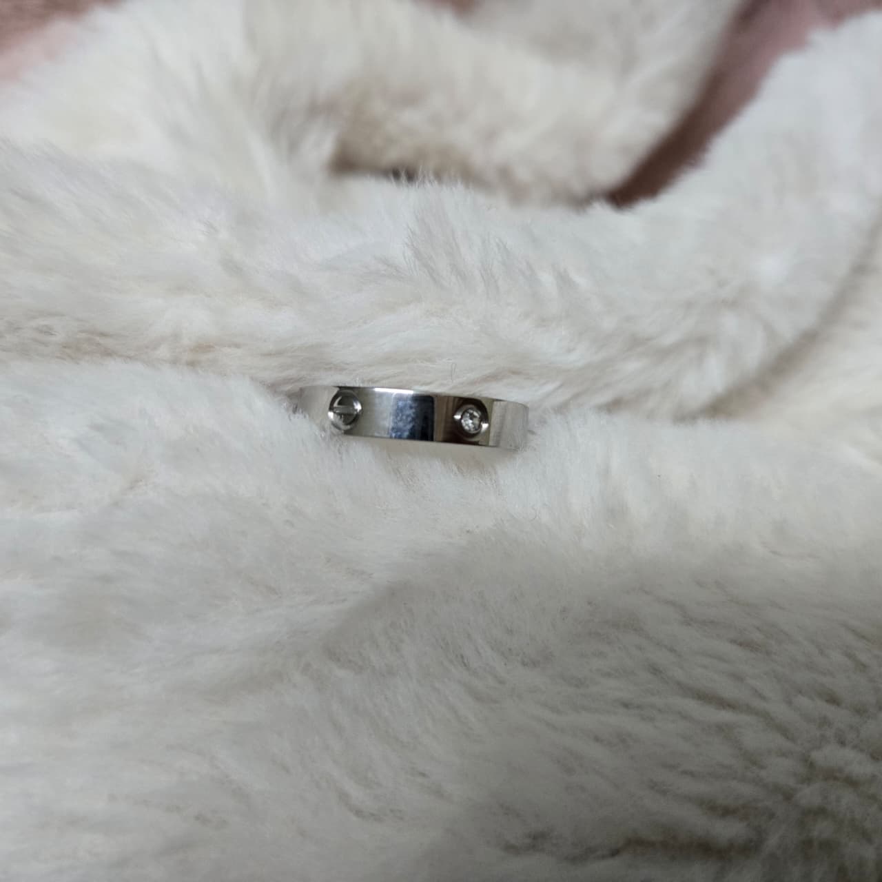 Silver ring with a small stone on a white fur surface