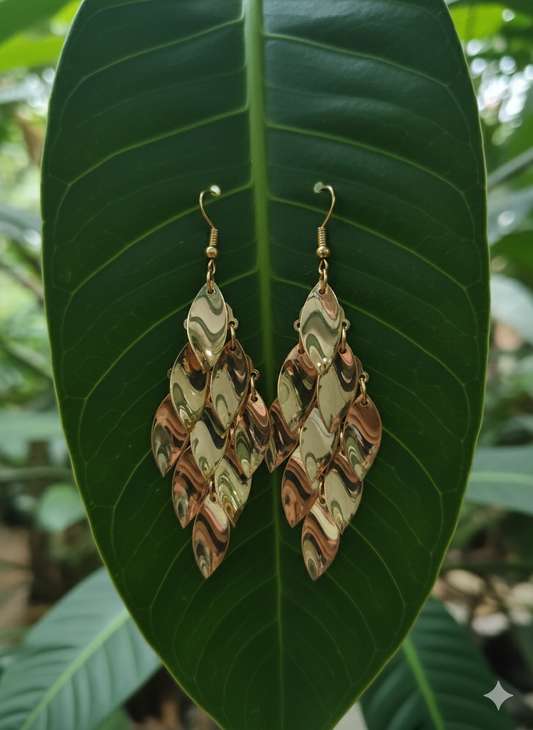 Pair of gold and green patterned earrings on a large green leaf.