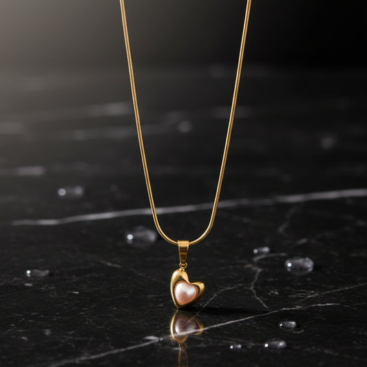Gold necklace with a heart-shaped pendant on a dark marble surface