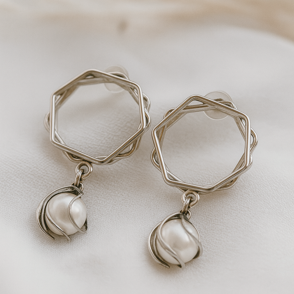 Silver geometric earrings with pearl-like droplets on a soft white background