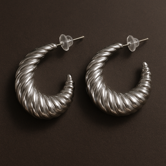 Pair of silver hoop earrings on a dark brown background