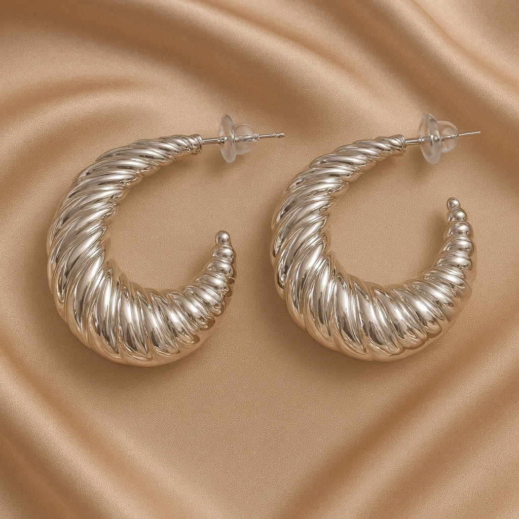 Silver hoop earrings on a beige satin background