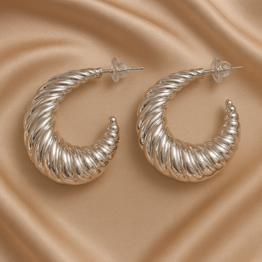 Silver hoop earrings on a beige satin background