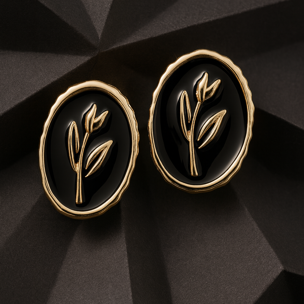 Elegant oval black and gold stud earrings with a raised botanical design on a glossy enamel finish