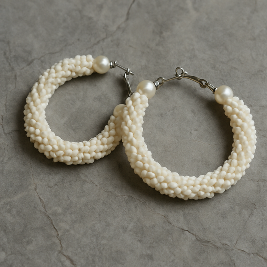 Pair of pearl hoop earrings on a gray stone surface