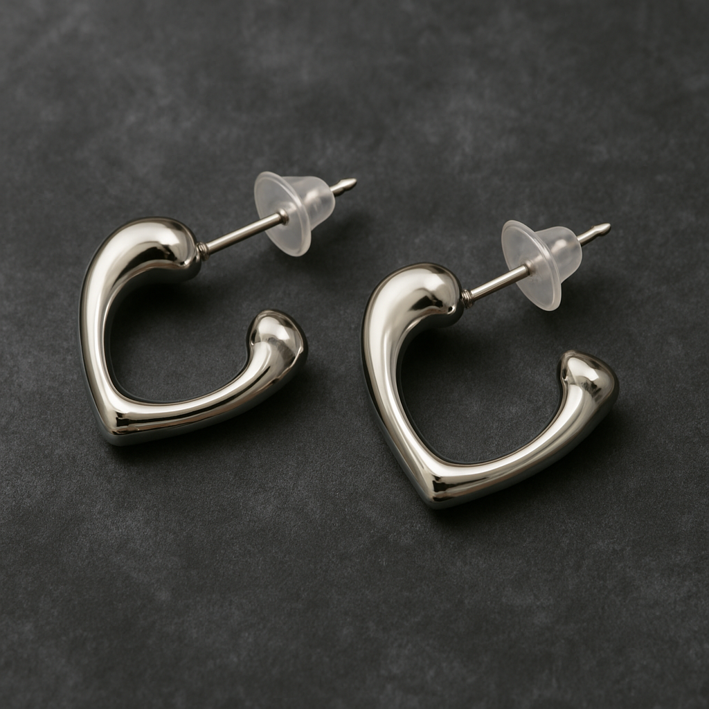 Pair of silver-toned open-heart stud earrings with a polished finish and transparent backings, displayed on a dark textured background.