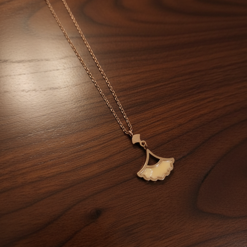 Gold necklace with a leaf pendant on a wooden surface