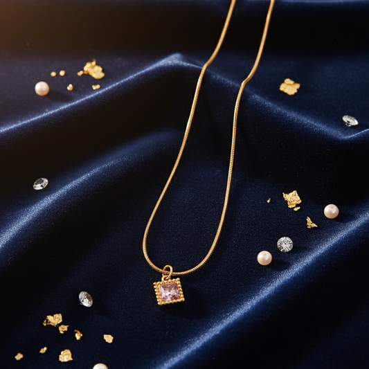Gold necklace with a square pendant on a dark blue fabric background