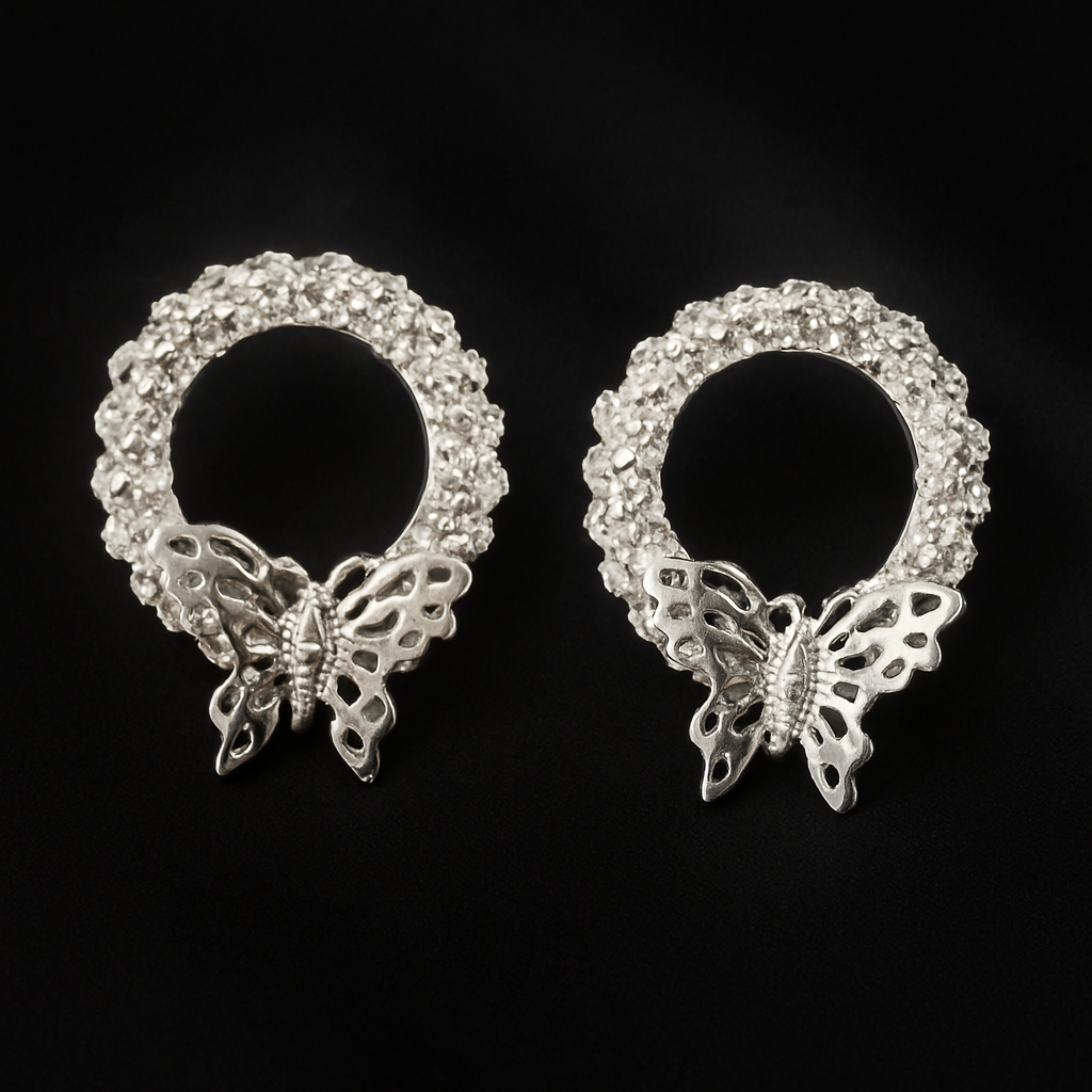 Silver-toned circular stud earrings featuring a textured, beaded design with a detailed butterfly charm at the base.