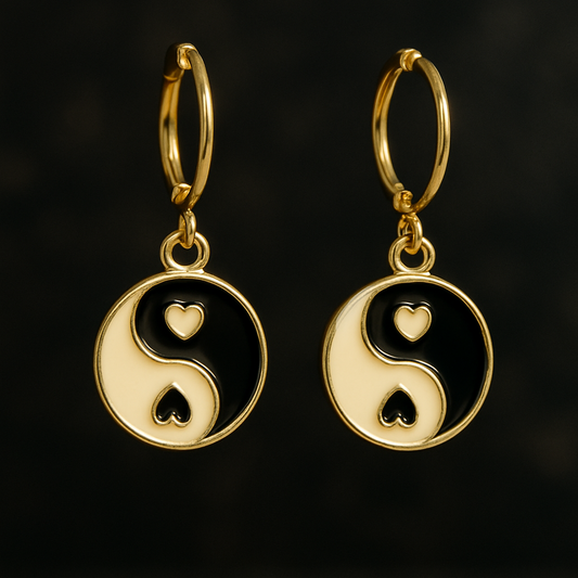 Gold earrings with yin yang design on a black background