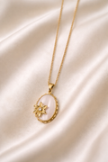 Gold necklace with a pendant on a white cloth background.