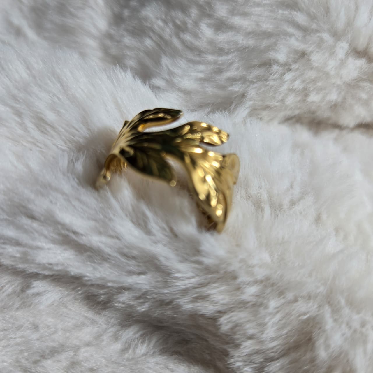 Gold butterfly-shaped ring on a white fur surface