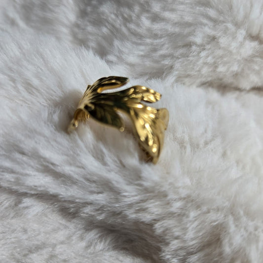 Gold butterfly-shaped ring on a white fur surface