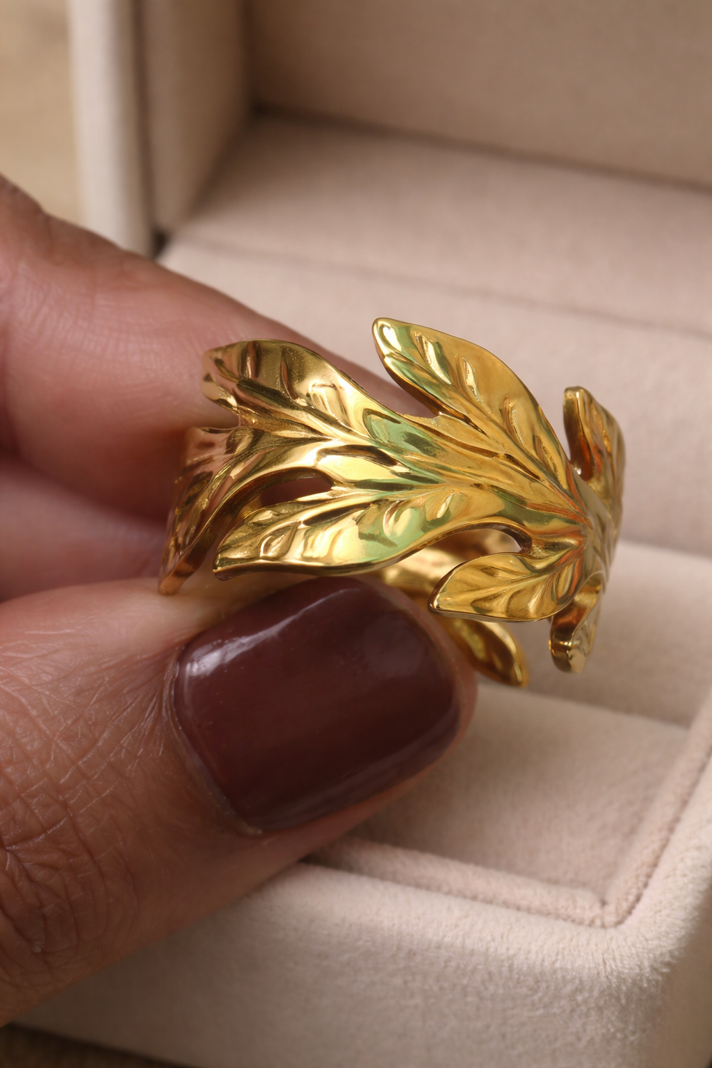 Gold leaf-shaped ring between the fingers of a woman  