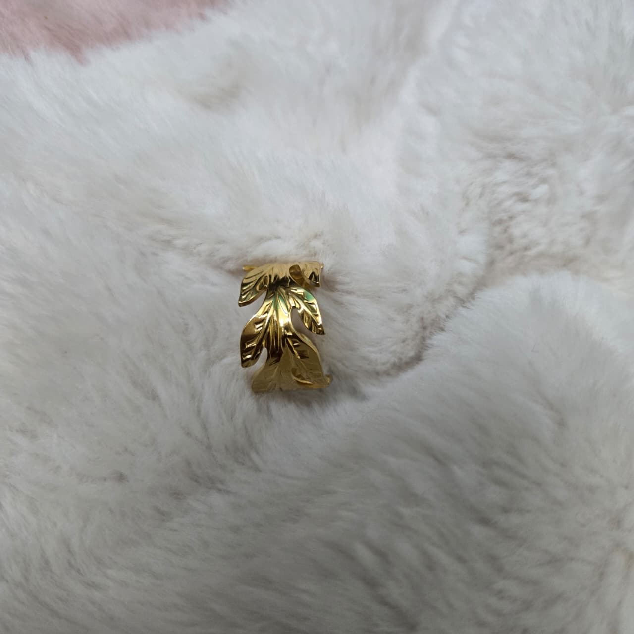 Gold leaf-shaped ring on a white fur background