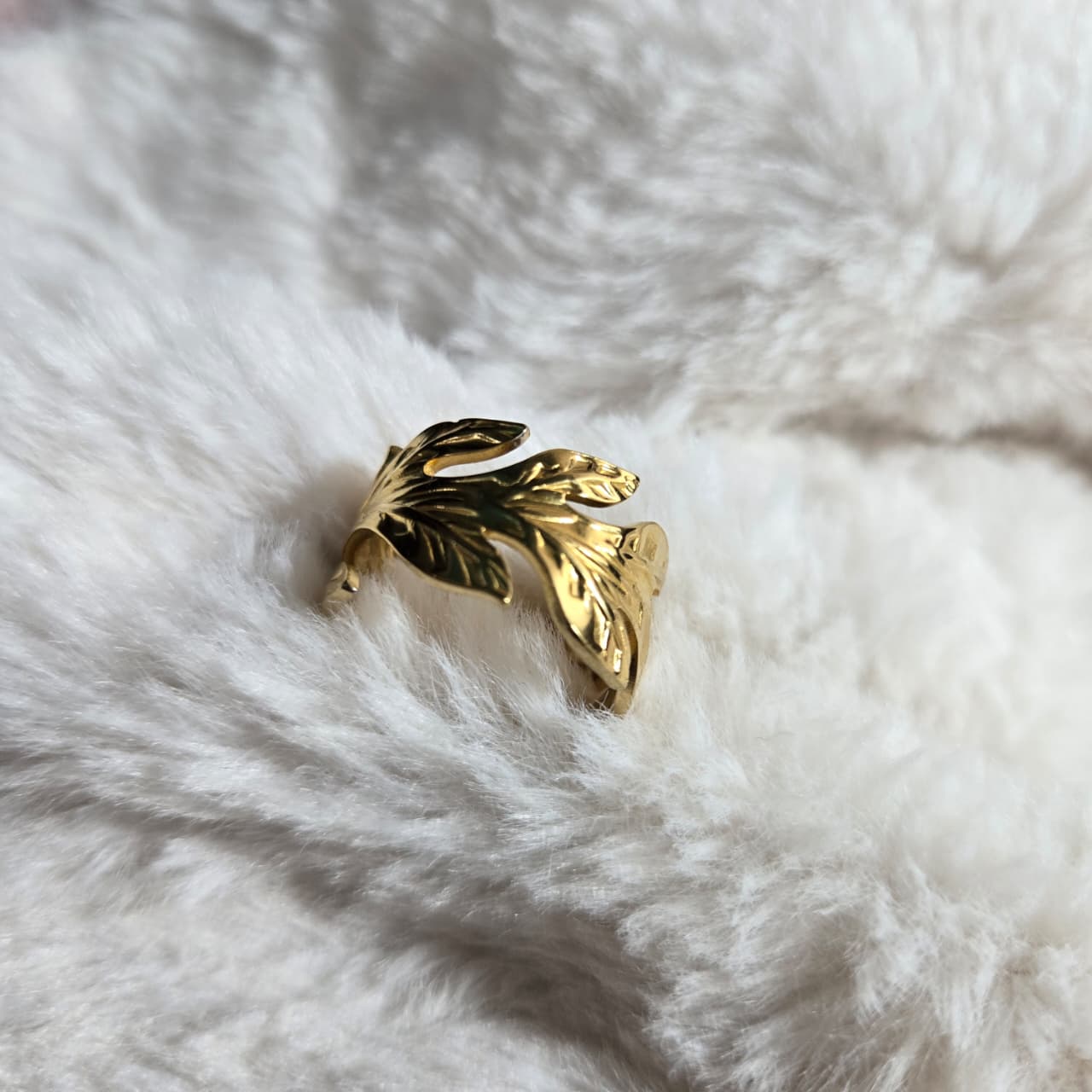 Gold leaf-shaped ring on a white fur surface