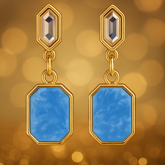 Gold earrings with blue stones on a golden bokeh background