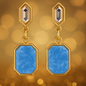 Gold earrings with blue stones on a golden bokeh background