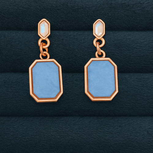 Pair of earrings with blue rectangular stones on a dark textured background