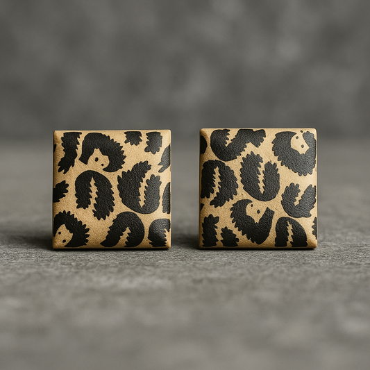 Two square coasters with black leaf pattern on a gray surface