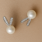 Pearl earrings with bunny ears design on a beige background