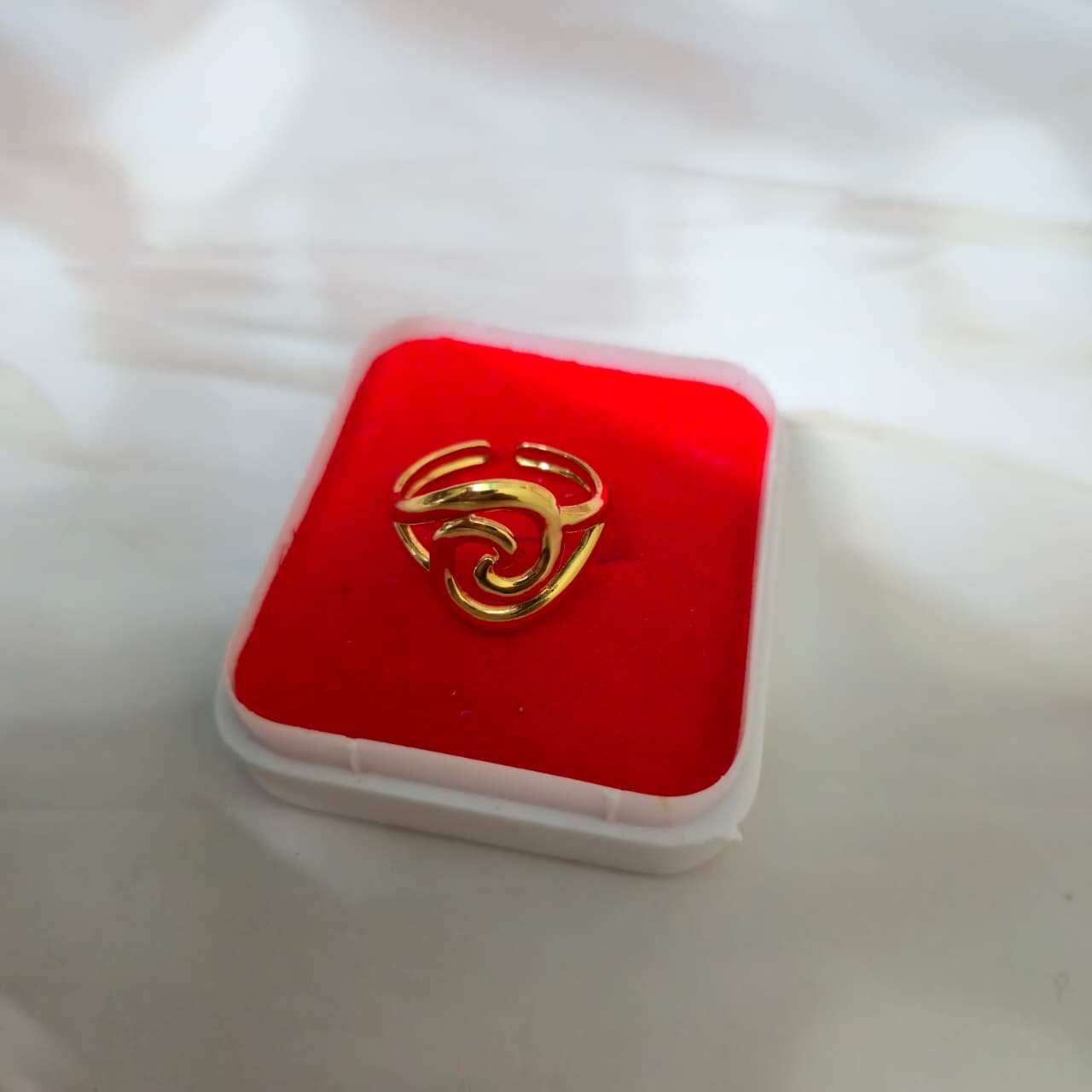 Golden heart-shaped swirl with a smooth, flowing spiral design on a red background, representing elegance and eternal love.