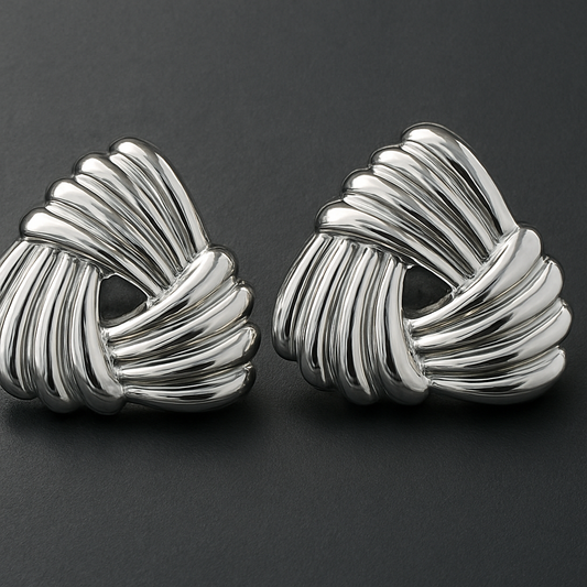 Pair of silver knot earrings on a dark gray background