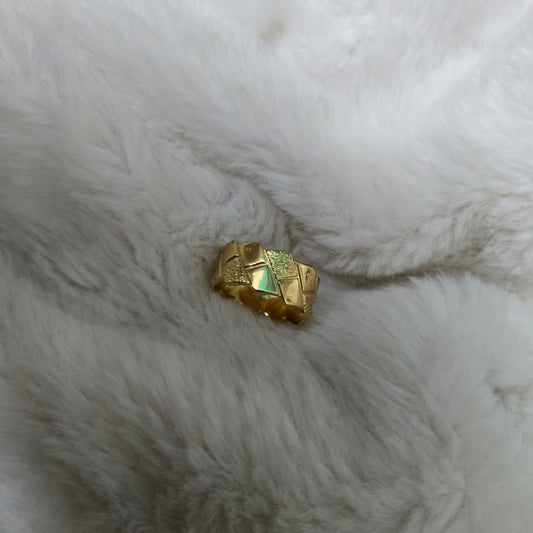Gold ring with a green gemstone on a white fur surface