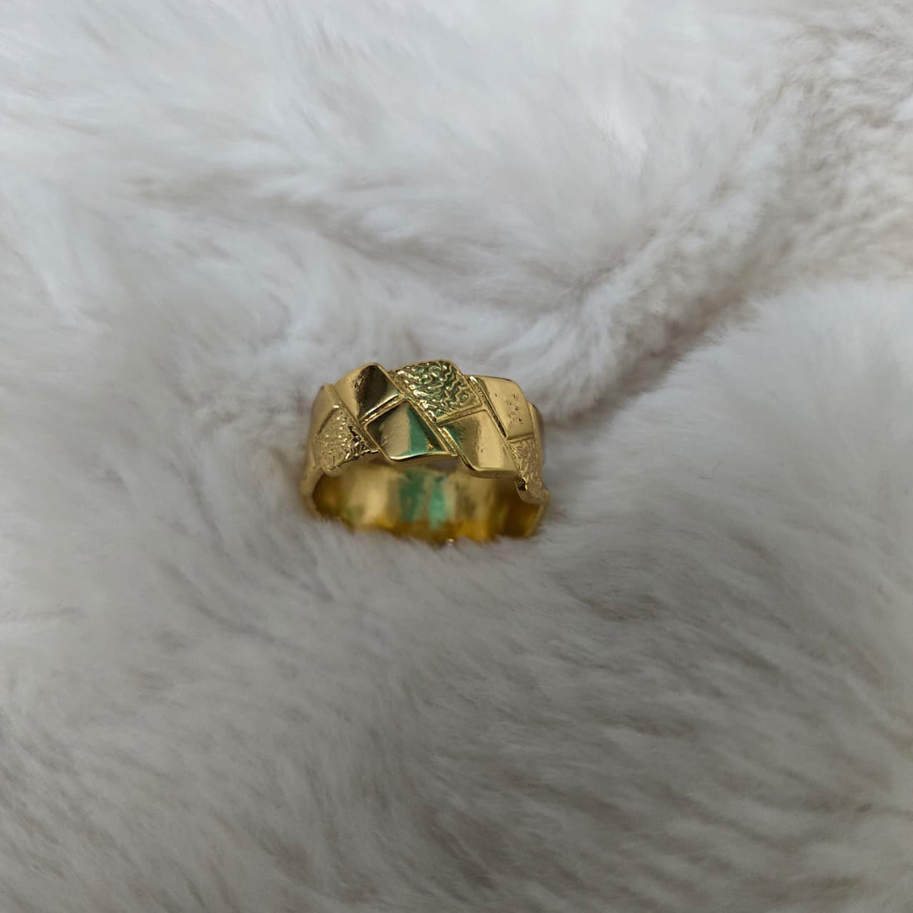 Gold ring with green stone on a white fur background