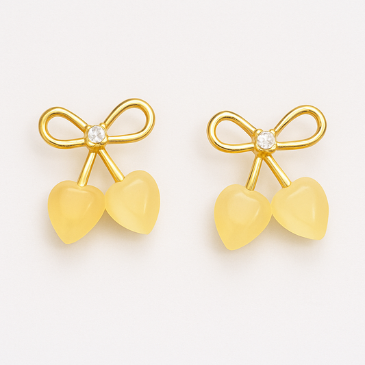 Gold-tone stud earrings featuring a bow design with a central crystal and two heart-shaped stone drops, resembling cherries.