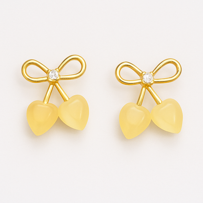 Gold-tone stud earrings featuring a bow design with a central crystal and two heart-shaped stone drops, resembling cherries.
