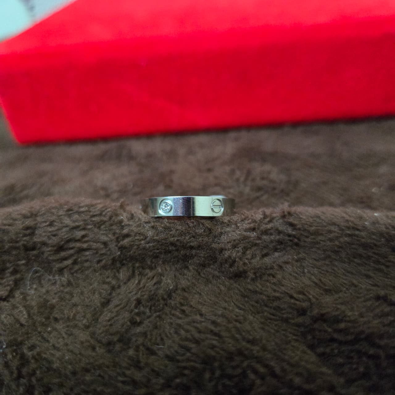 Silver ring with engraved design on a brown textured surface