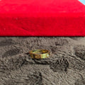 Gold ring with a diamond on a textured surface with a red background
