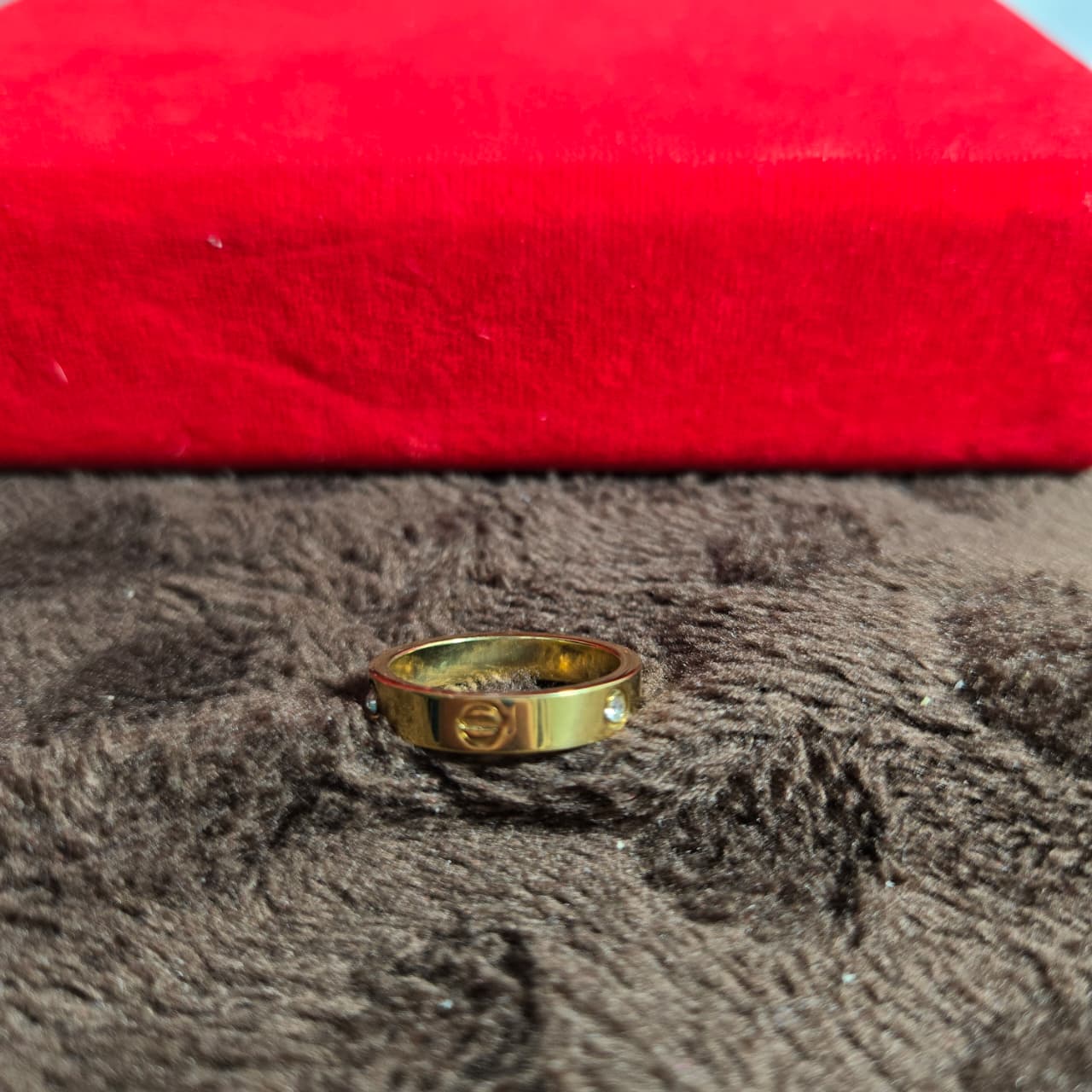Gold ring with a diamond on a textured surface with a red background