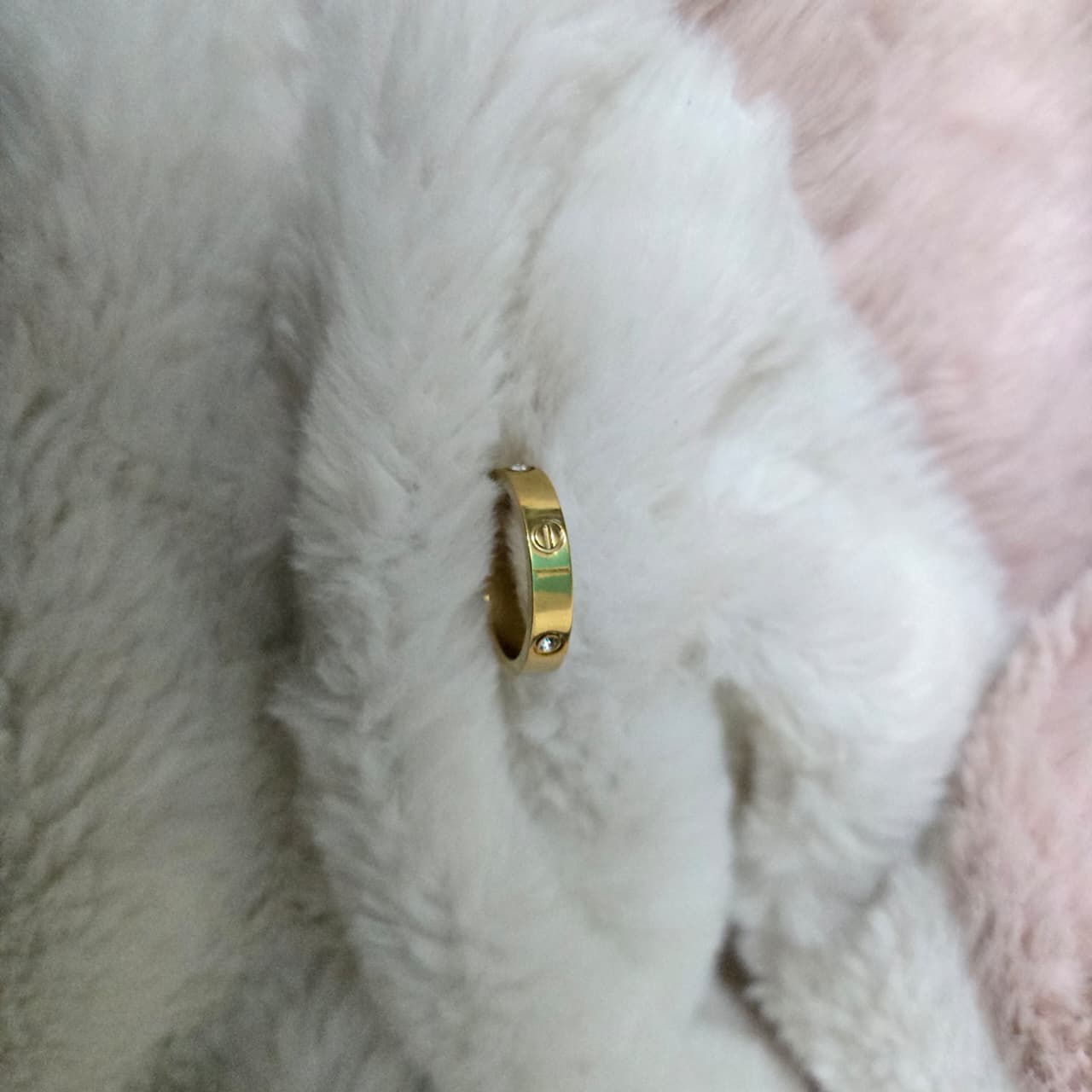 Gold ring with a green stripe on a textured white and pink fabric background