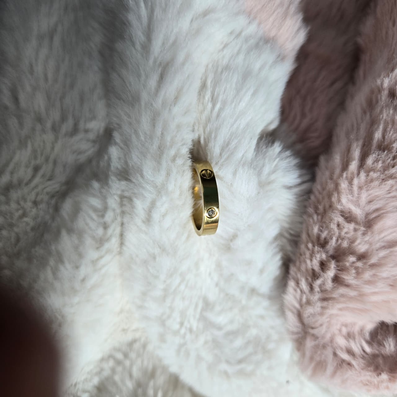 Gold ring with a black center and diamond on a fluffy white surface