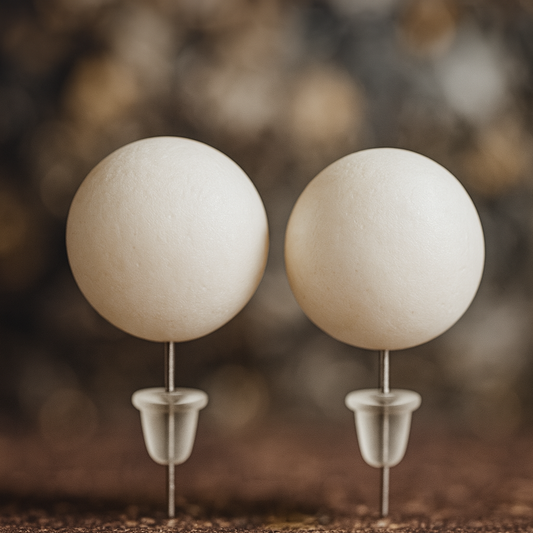 Two white spherical objects on metallic stands against a blurred natural background