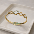 a bracelet with premium gold-tone finish with a blend of white mother-of-pearl and mint green enamel accents on a white plate.