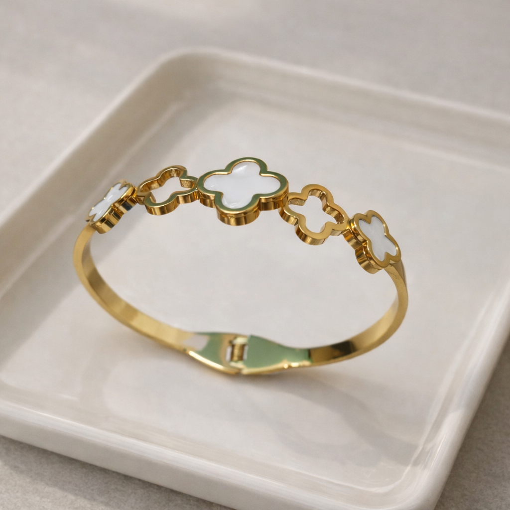 a bracelet with premium gold-tone finish with a blend of white mother-of-pearl and mint green enamel accents on a white plate.