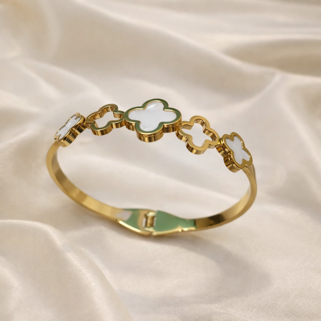 a bracelet with premium gold-tone finish with a blend of white mother-of-pearl and mint green enamel accents on a white cloth.
