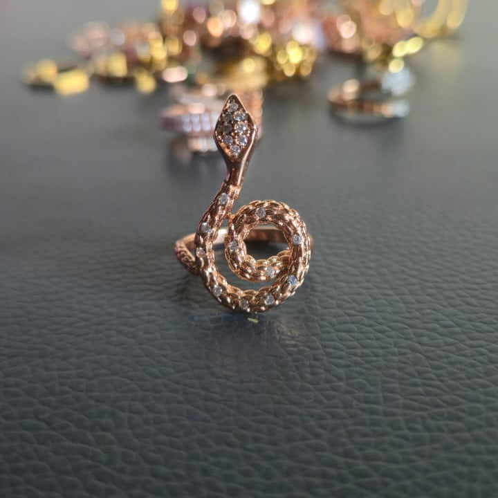 Rose gold spiral pendant on a dark surface with blurred colorful background