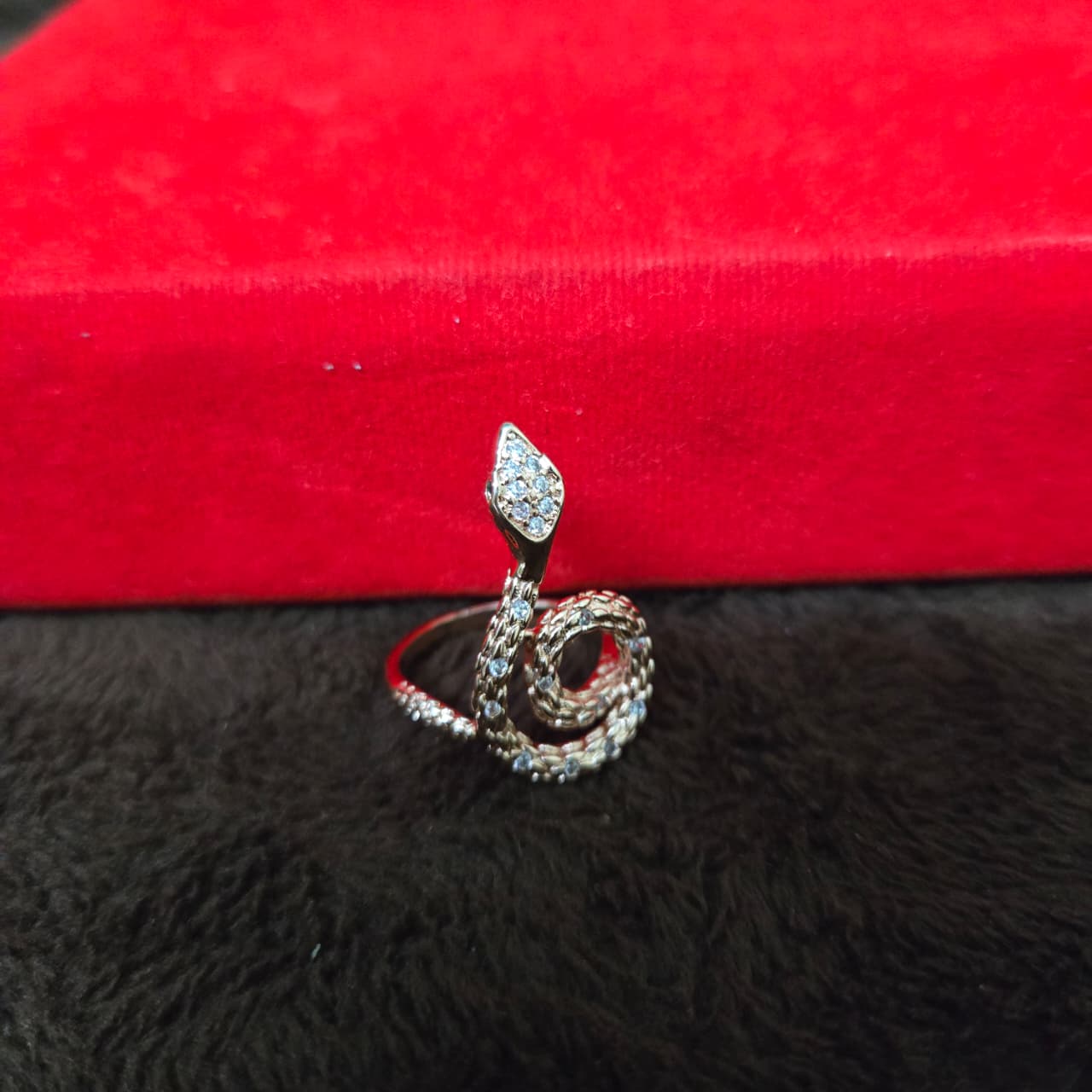 Silver ring with a diamond-shaped design on a red and black textured surface