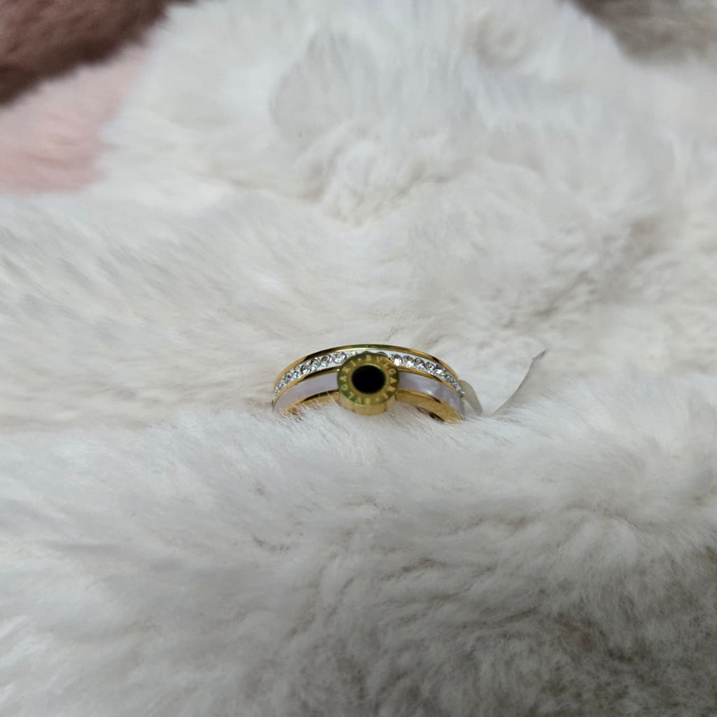 Gold ring with a green gemstone on a white fur surface