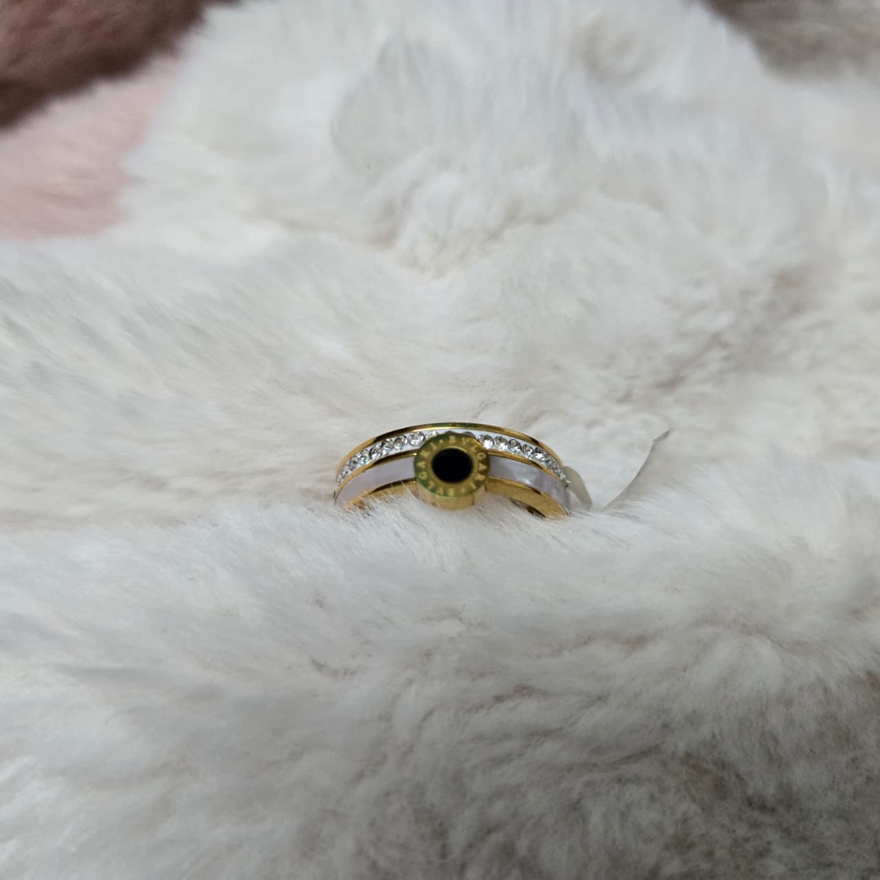 Gold ring with a green gemstone on a white fur surface