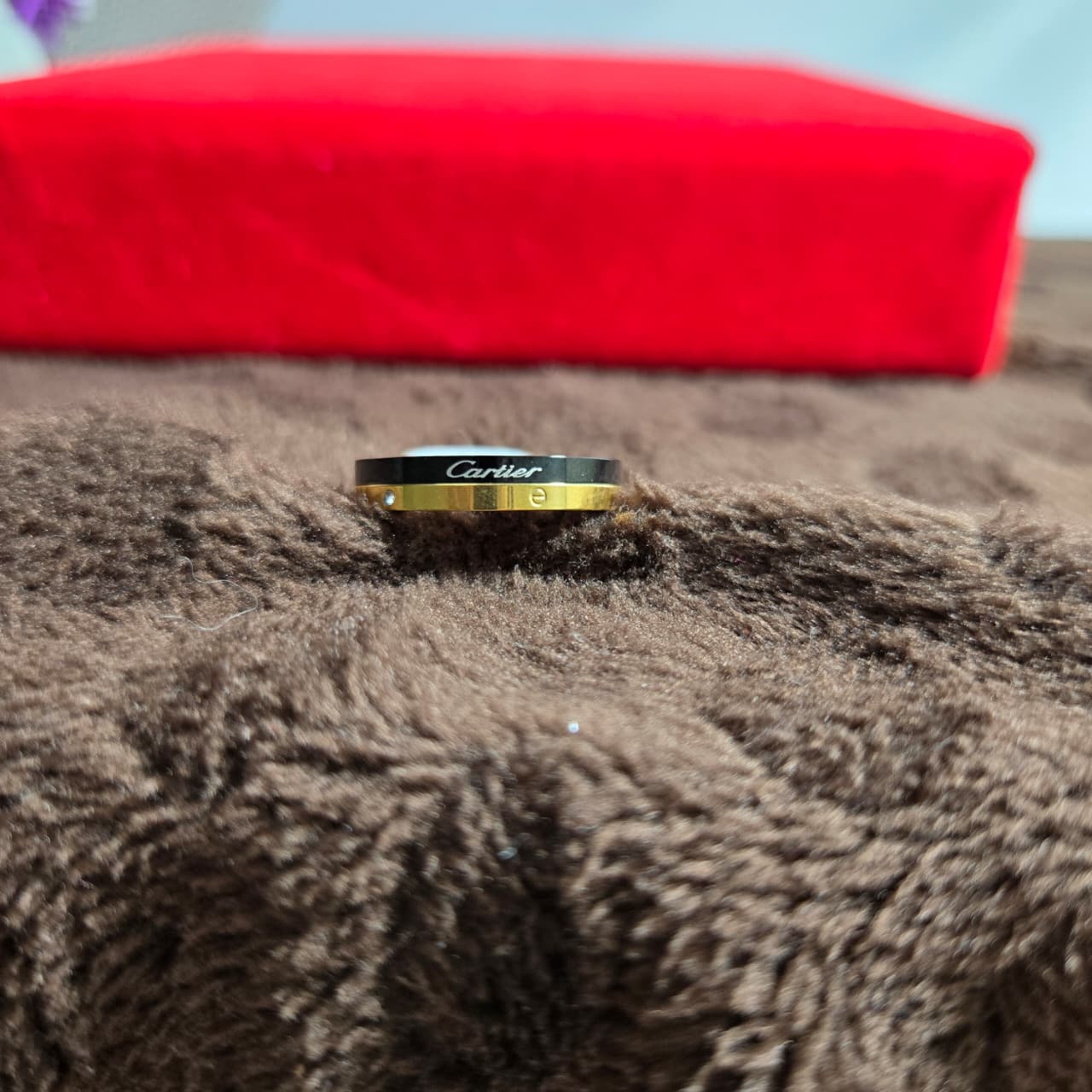 Gold bracelet with Cartier logo on a brown surface