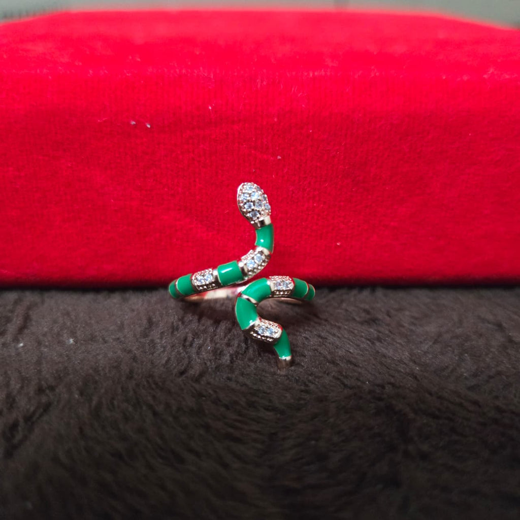 Green snake-shaped ring with rhinestones on a red and black textured background