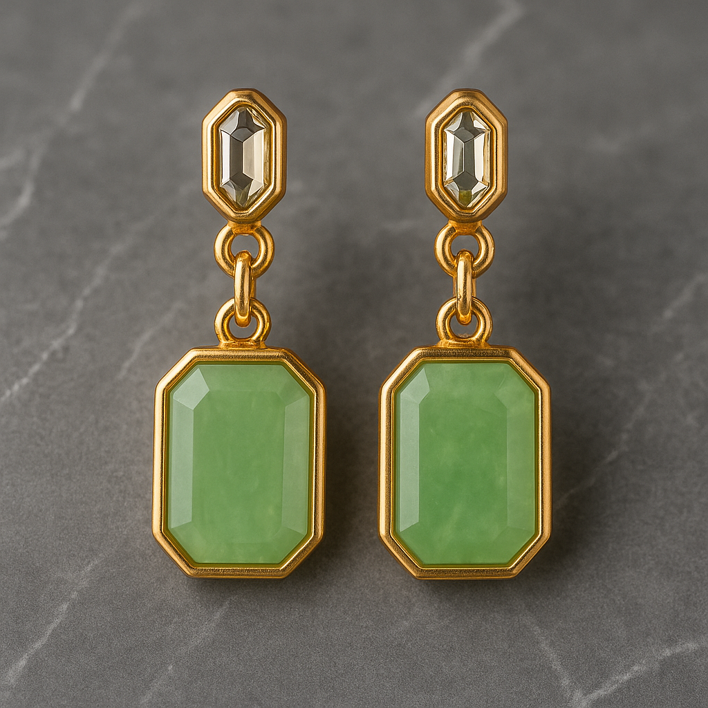 Gold earrings with green gemstones on a gray background