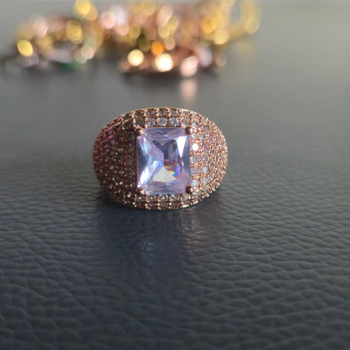 Rose gold ring with a purple gemstone on a dark surface