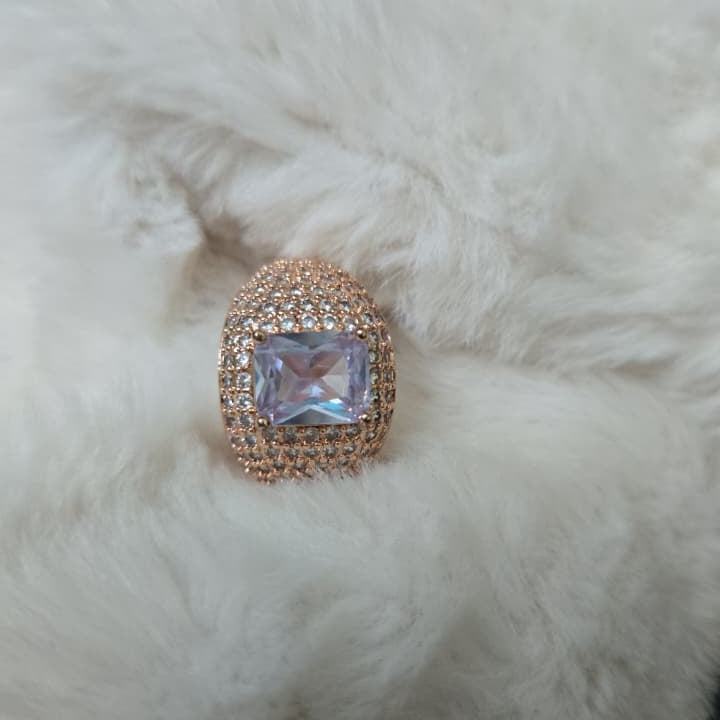 Rose gold ring with a large gemstone on a fluffy white surface